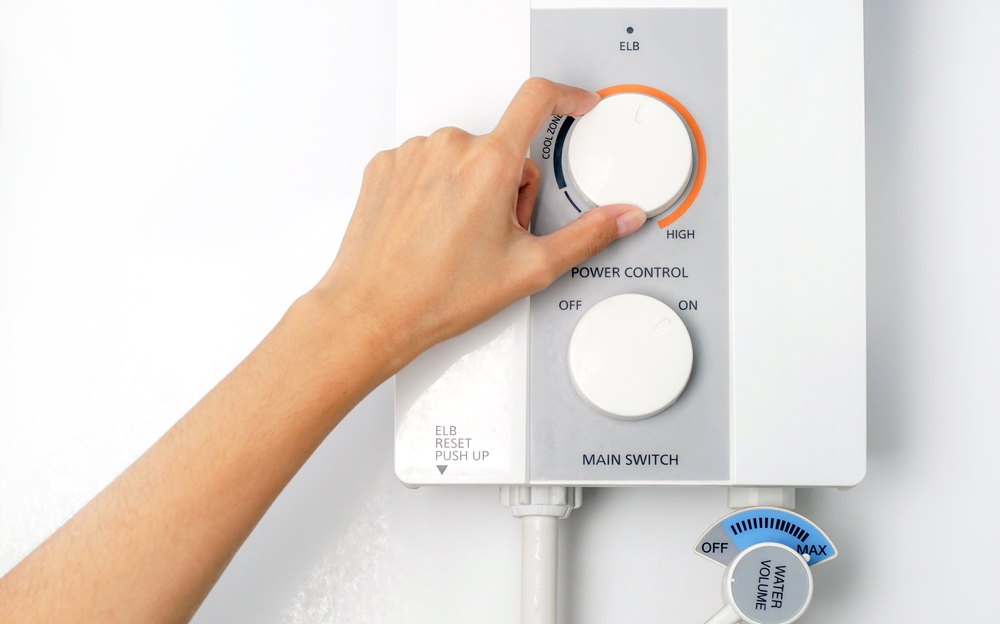 A homeowner adjusts the temperature control on their tankless water heater