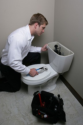 Applewood employee fixing a toilet