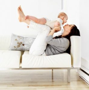 mother kissing her baby on couch