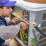 A tech repairs an air conditioner.