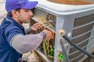 A tech repairs an air conditioner.