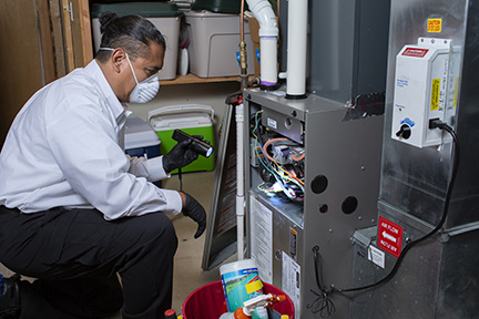 man in light blue shirt inspects an HVAC system