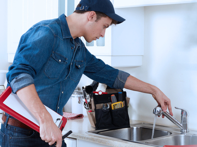 plumber testing the water flow of a kitchen faucet