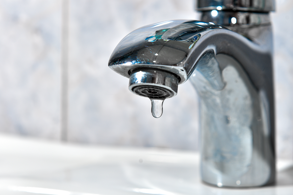 A drop of pure water dripping from the tap. Selective focus.