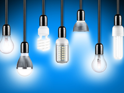 various types of lightbulbs hanging from black cords over a blue background
