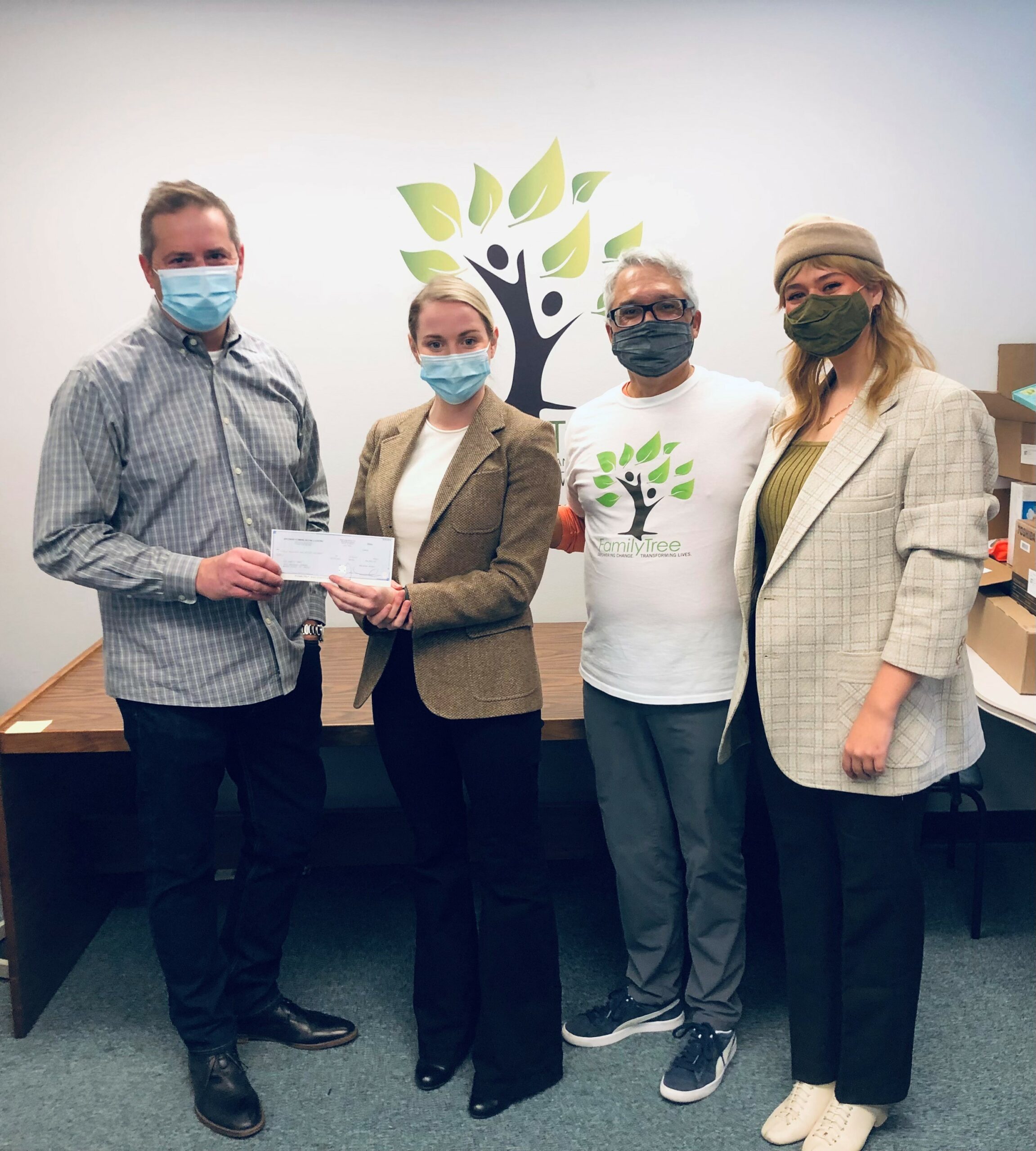 Four Family Tree Holidays of Hope recipients holding a $5,000 check from Applewood's charitable giveaway