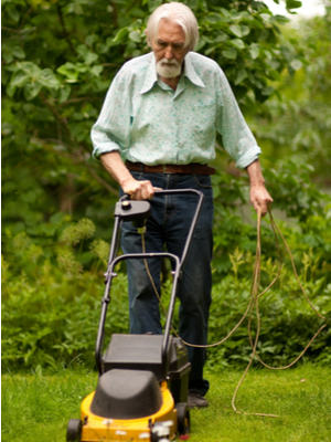 A man uses an electric mower with outdoor extension cord
