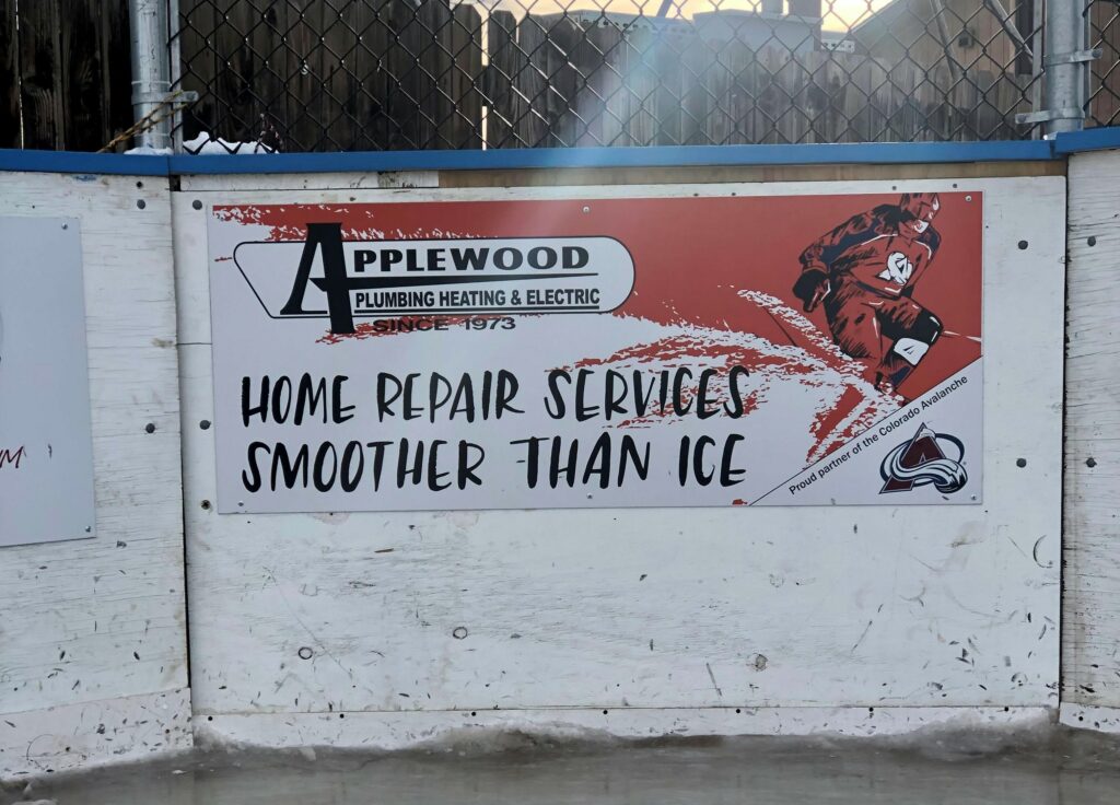 Home Repair Services Smoother Than Ice banner attached to a hockey rink board