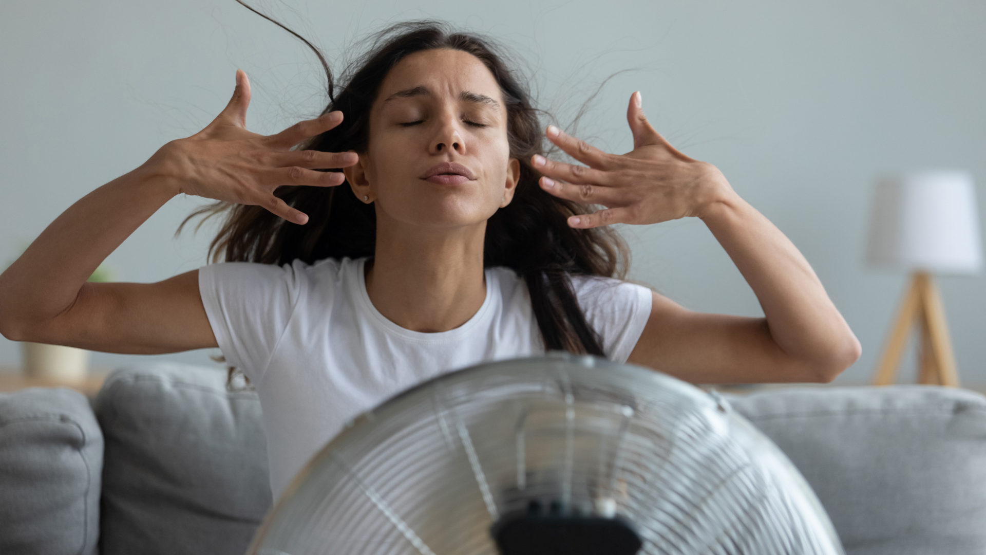 Person standing in front of a fan that is blowing on their face.