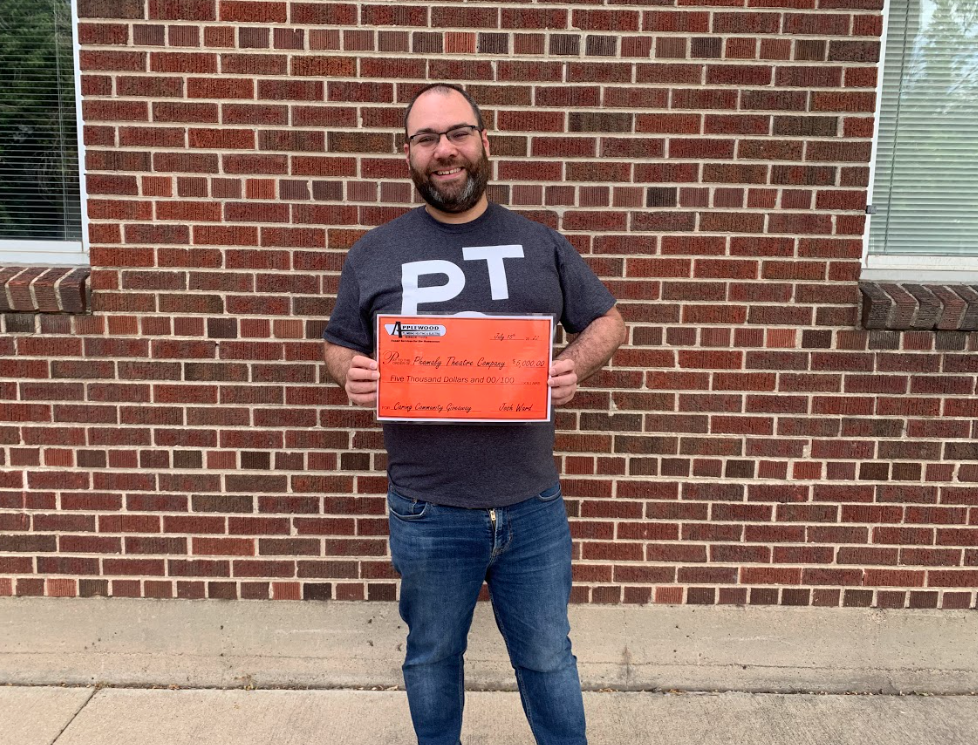 Man holding the Applewood Caring Community Giveaway check.