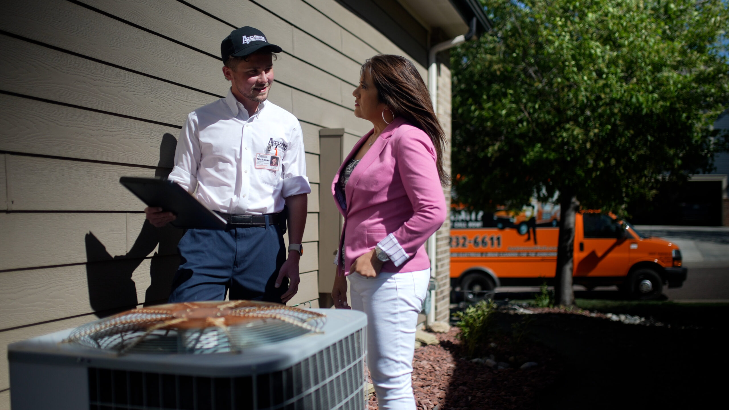 Applewood employee talking to a customer outside by an air conditioner.