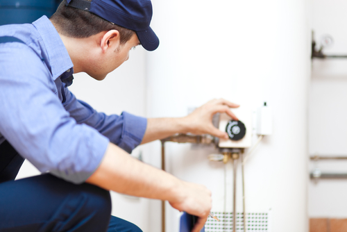 A licensed plumber checks the settings on a water heater.