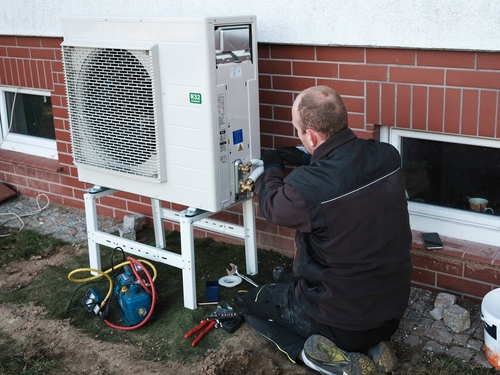 A technician cleans a home heat pump.