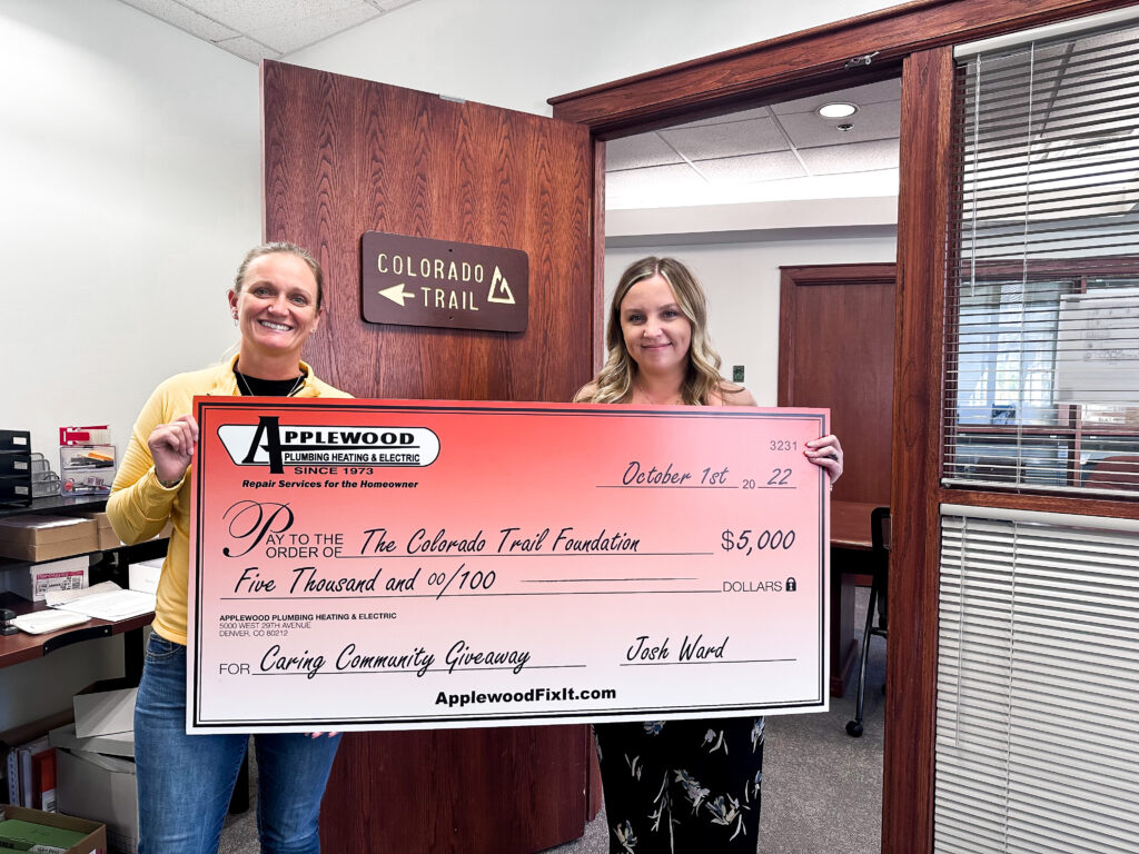 Two Applewood employees holding a large check.