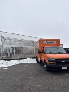 Applewood truck parked outside of a snow lined greenhouse.