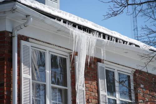 A large ice dam tears at a home's soffit.