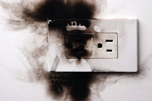 The blackened exterior of a faulty wall electrical outlet. 