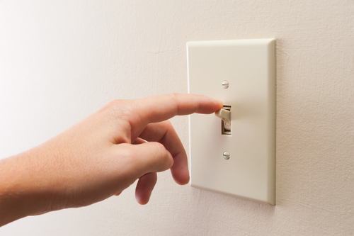 A person feels a warm light switch when turning off their light.