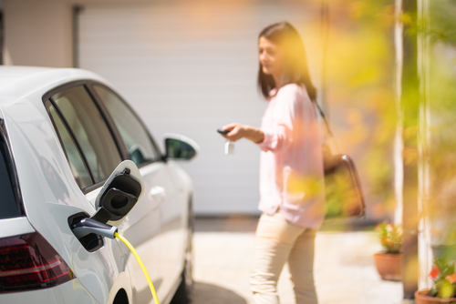 A woman unlocks her fully charged vehicle in her driveway.