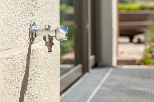 A shiny new outdoor faucet on a home's patio.