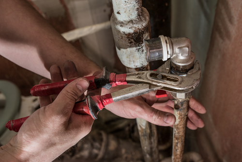 A plumber loosens old corroded pipes to replace them.