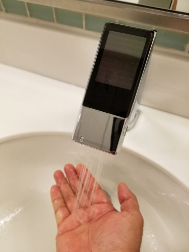 A homeowner washes their hands beneath a touchless bathroom faucet.