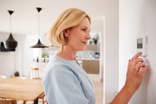 A home owner adjusts their smart thermostat. 
