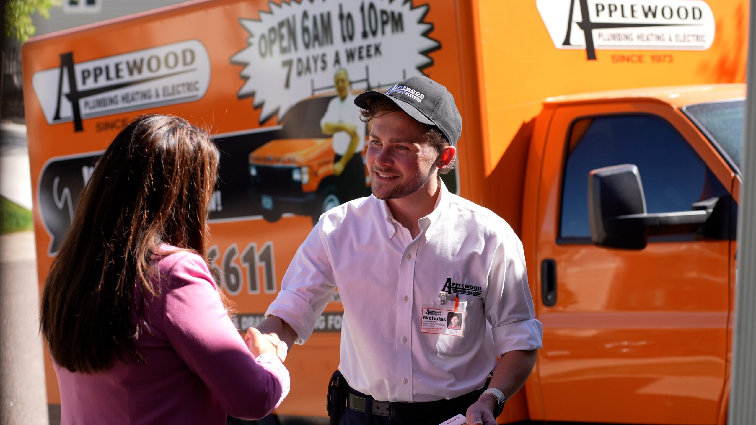 two people shaking hands in front of orange truck