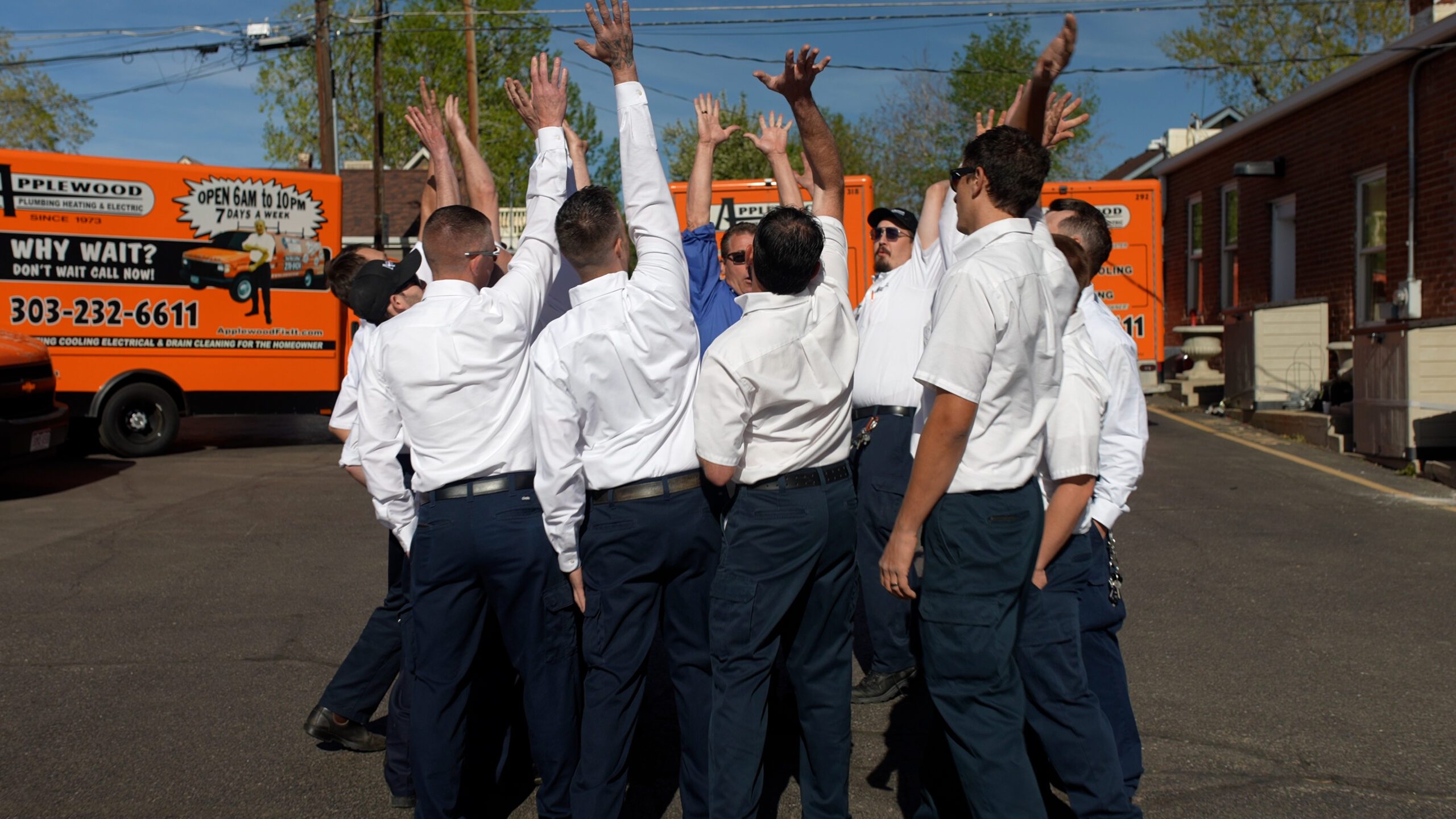 applewood employees gathered in a circle with hands in the air