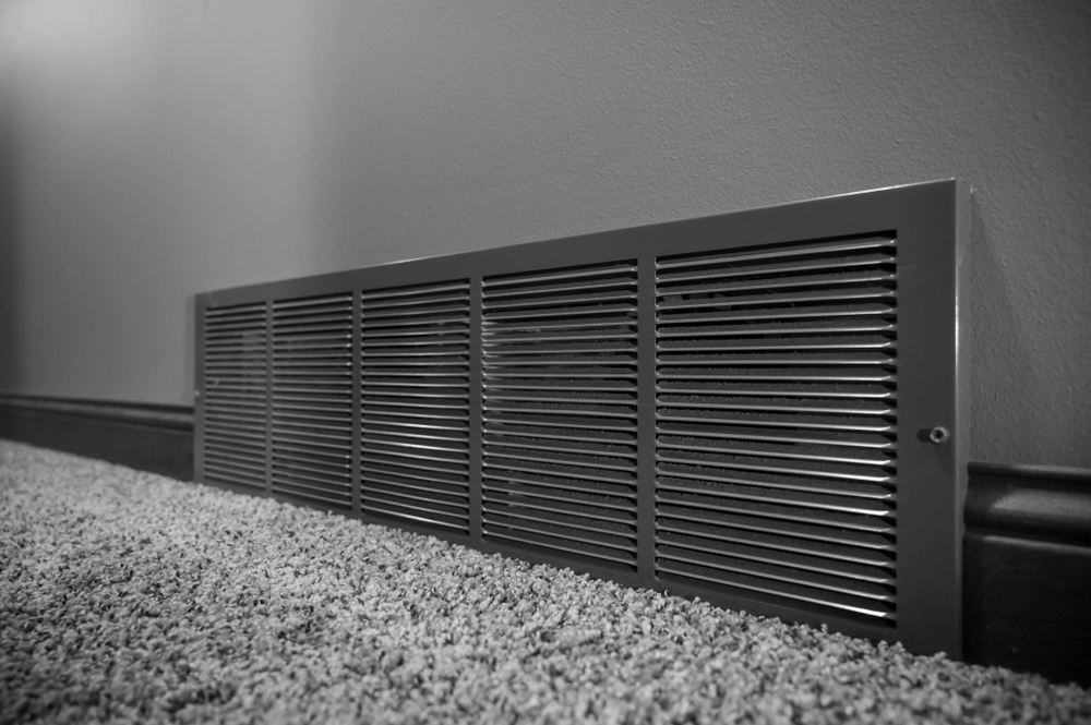 A gray cold air return vent along a home’s baseboard.
