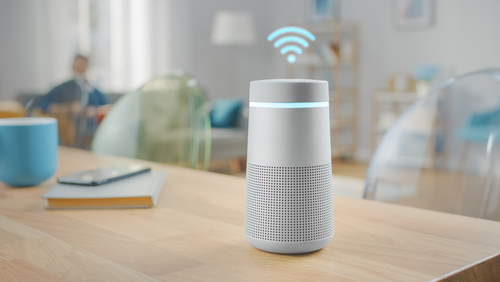 A smart home device sits on a wooden table in a living room.